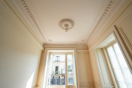 Moulures et rosace en plâtre au plafond d'un appartement haussmannien parisien avec parquet en chevrons